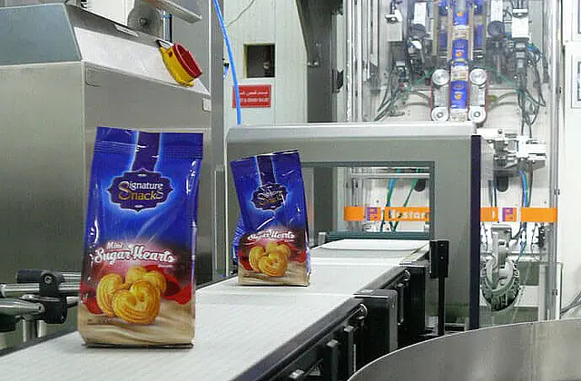 Cookies packed in bags are transported away on a conveyor belt of the packaging line