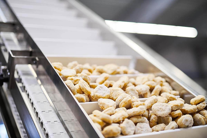 Sistemas de envasado con cinta transportadora para alimentos frescos y congelados Alimentos sin envasar como nuggets pasados por una cadena de montaje
