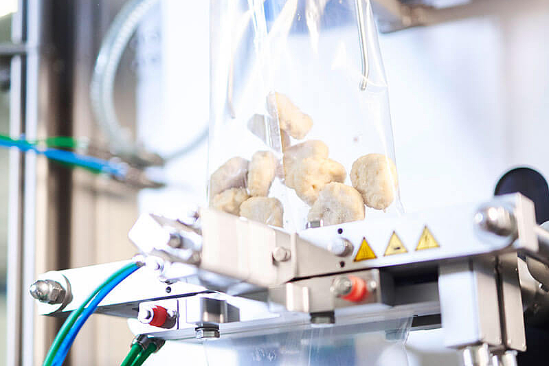 Vertical form fill and seal machine for bag packing Detail view of vertical form fill and seal machine with chicken nuggets in two transparent bags