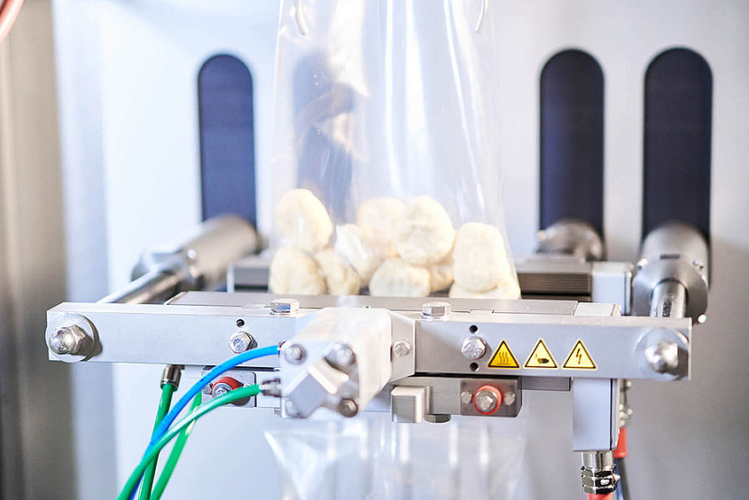 Gefrorene Lebensmittel werden maschinell in vertikalen Schlauchbeuteln verpackt