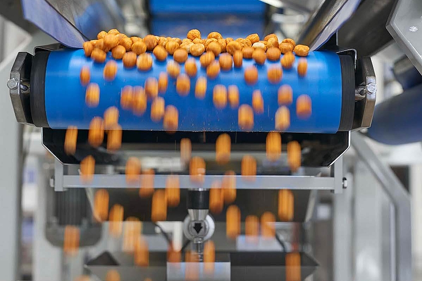Sistema de distribución de aperitivos y galletas A través de una cinta transportadora de un sistema de distribución se distribuyen pequeños aperitivos