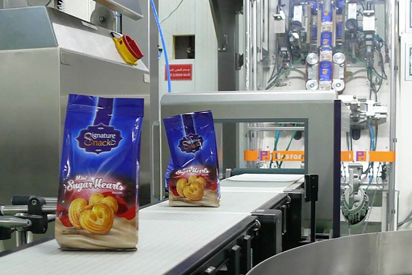 Sistema de envasado con cinta transportadora para el transporte de galletas Dos bolsas de galletas envasadas se transportan mediante cintas transportadoras.