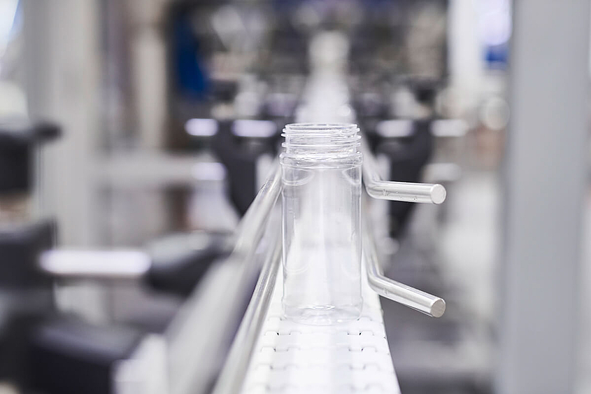 Cinta transportadora de un sistema de alimentación para envases de confitería Un vaso vacío es transportado por la cinta transportadora de una envasadora
