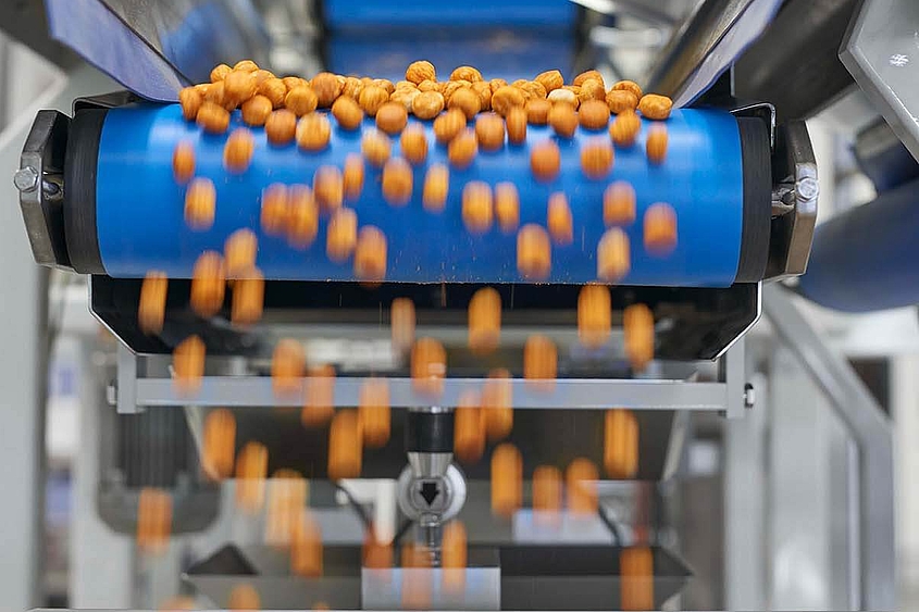 Über ein Laufband eines Verteilsystems werden kleine Snacks weiterverteilt