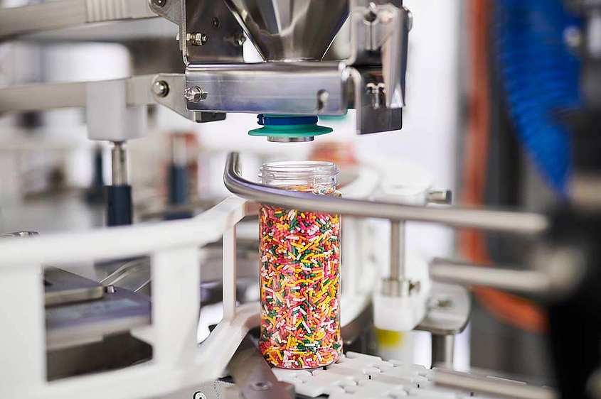 Bunte Süßwaren in Verpackungsmaschine abgefüllt in einem Glas